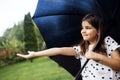 A little girl stands with a black umbrella in the rain. A cute baby stretches out her hand and catches raindrops in the park Royalty Free Stock Photo