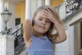 A little girl stands with her hair fluttering in the wind against the backdrop of a historic building. Royalty Free Stock Photo