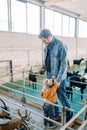 Little girl stands hugging her father leg and looks at the goat in the corral