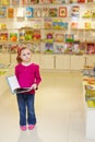 Little girl stands looking thoughtful holding open book