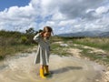 Little girl stands in a muddy puddle straightening her hair with her hand