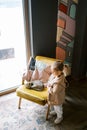 Little girl stands near a chair with a sleeping tabby cat and looks away