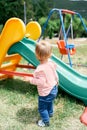 Little girl stands near the children slide in the playground Royalty Free Stock Photo