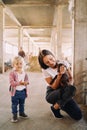 Little girl stands near her mother squatting down with a goatling in her arms Royalty Free Stock Photo