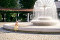 Little girl stands near a large spherical fountain in the park