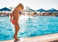 A little girl stands near the pool and tries the water with her foot Royalty Free Stock Photo
