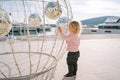 Little girl stands near a spherical Christmas installation with mirror balls