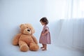 Little girl stands next to a big teddy bear Royalty Free Stock Photo