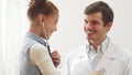 A small patient listens to the doctor`s breath with a stethoscope