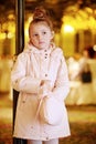 Little girl stands pensively fumbling in handbag