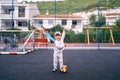 Little girl stands on the playground lifting a toy car on a rope Royalty Free Stock Photo