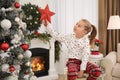 Little girl with star topper near Christmas tree indoors Royalty Free Stock Photo