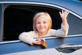 A little girl is sticking her head out the car window. Road trip or travel concept. Happy kids travel by the car. Cute Royalty Free Stock Photo