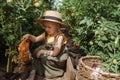 A little girl in a straw hat is picking tomatoes in a greenhouse. Harvest concept.