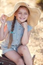 Little girl in a straw hat,resting sitting on a suitcase Royalty Free Stock Photo