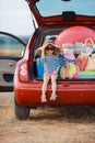 Little girl in straw hat sitting in the trunk of a car Royalty Free Stock Photo