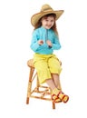 Little girl in straw hat sitting on wooden chair