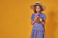 Little girl in a straw hat and sunglasses is smiling on a yellow background. child girl in a blue dress is holding a Royalty Free Stock Photo