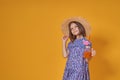 Little girl in a straw hat and sunglasses is smiling on a yellow background. child girl in a blue dress is holding a Royalty Free Stock Photo