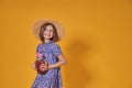 Little girl in a straw hat and sunglasses is smiling on a yellow background. child girl in a blue dress is holding a Royalty Free Stock Photo