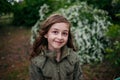 Little girl on the street against a background of green foliage. Girl with long hair. Child 9-10 years old girl