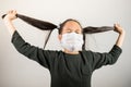 Little girl stretches her pigtails desperately and wildly. Little girl locked up at home during quarantine coronavirus. Concept Royalty Free Stock Photo