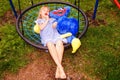 Little girl in a striped dress on a spider web swing. Lollipop in mouth.