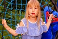 Little girl in a striped dress on a spider web swing. Lollipop in mouth.