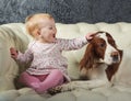 Little girl stroking big dog, on white sofa