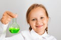 Little girl student holds in his hand a flask with liquid and looks at the camera. A child is conducting a chemical experiment