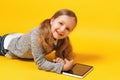 Little girl student is lying on the floor with a tablet. Royalty Free Stock Photo
