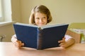 Little girl student sits at a desk with book. School, education, knowledge and children Royalty Free Stock Photo