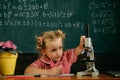 Little girl study in biology classroom at school. Schoolgirl work on biology research with microscope