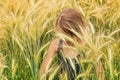 Little girl submerged under the spikes of a ripening grain field