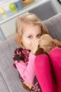 Little girl sucking thumb hugging toy dog