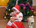 The little girl in a suit of the Little Red Riding Hood and a figurine Santa Claus about a New Year tree Royalty Free Stock Photo