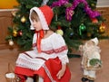 The little girl in a suit of the Little Red Riding Hood and a figurine Santa Claus about a New Year tree Royalty Free Stock Photo