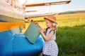 A little girl with a suitcase and stands on the tarmac near the planes. She`s going on a trip