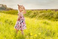 little girl in summer dress with pigtails in a green field, warm rays of the sun Royalty Free Stock Photo