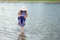 Little girl in summer hat and beautiful dress standing in river Royalty Free Stock Photo