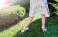 Little girl in a summer sarafan stays on a green lawn