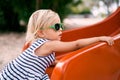 Little girl in sunglasses climbs a children slide