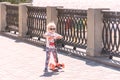 Little Girl in sunglasses driving a scooter