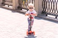 Little Girl in sunglasses driving a scooter