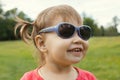 Little girl in sunglasses playing in park in front of green grass Royalty Free Stock Photo