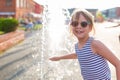 Little girl in sunglasses playing by the streams of the city fountain Royalty Free Stock Photo