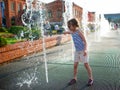 Little girl in sunglasses playing by the streams of the city fountain Royalty Free Stock Photo
