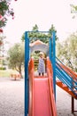 Little girl in sunglasses stands on a children slide