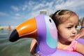 Little girl swimming in the sea with inflatable ring like toucan in summer day Royalty Free Stock Photo