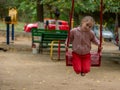 Children's playground in the city park. A 7-8 year old girl is swinging on a swing